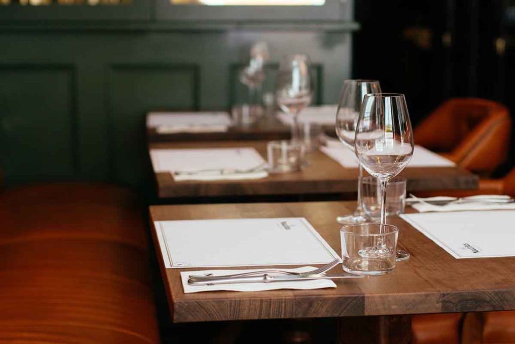 Restaurant interior, closeup of tables set with wine glasses and silverware